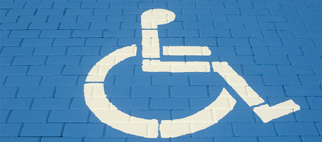 Weißes Rollstuhl-Symbol auf blauem Pflaster 